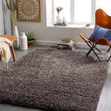 Living room scene with a charcoal Siari Solid Shag Rug, leather chair, and neutral decor. Roomscene-Rectangle