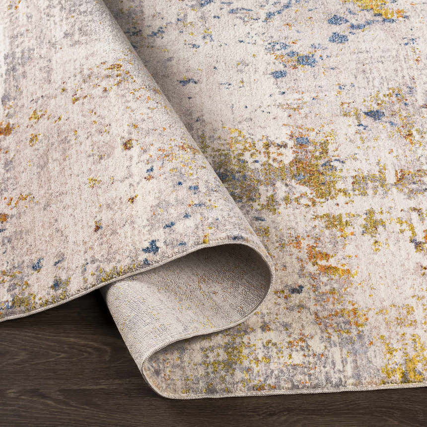 Close-up of the Palhi Area Carpet, a contemporary rug in cream, blue, gray, and mustard, with a machine-woven texture. Fold