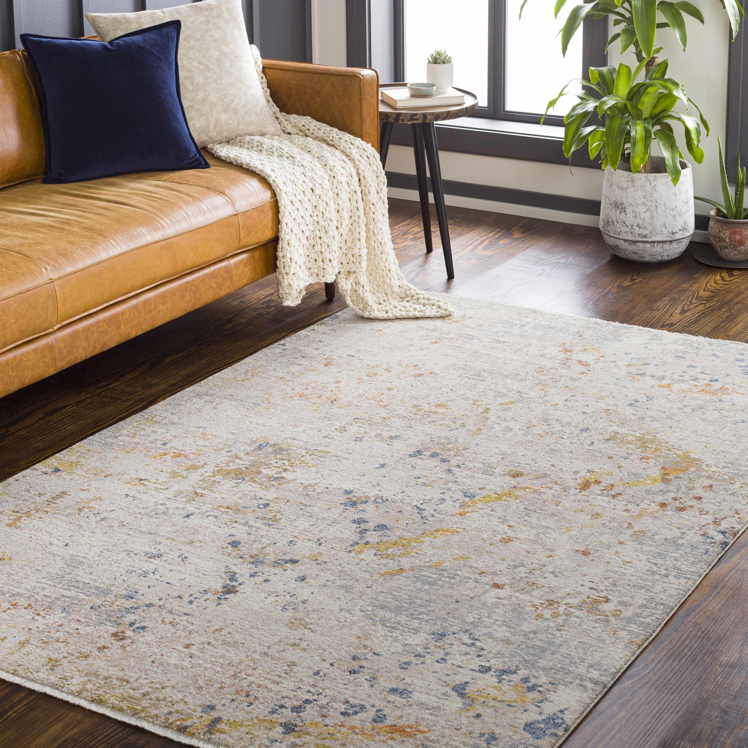 Living room scene with a Palhi Area Carpet, tan leather sofa, and dark wood floors. Contemporary style. Roomscene-Rectangle