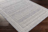 Close-up of the Panaytayon Area Rug showing a contemporary geometric pattern in cream and navy on dark wood floors. Corner