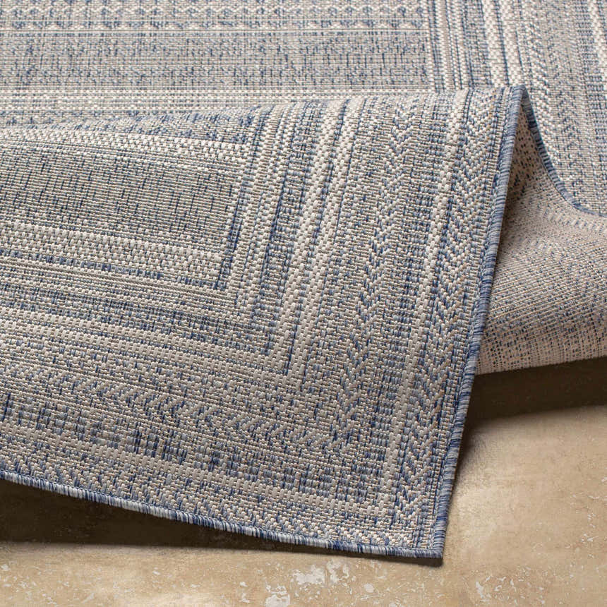 Close-up of the Panaytayon Area Rug showcasing its blue and cream woven pattern and textured edge. Fold