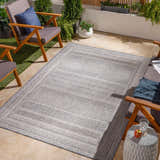 Outdoor patio scene with a charcoal and cream Panaytayon area rug, wood chairs, and potted plants. Roomscene-Rectangle