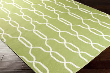 Close up of Penasco Area Carpet, a hand woven wool rug in cream and green with a geometric trellis pattern. Corner