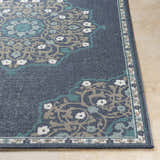Close-up of the Penland Area Rug. Navy rug with pale blue, taupe, teal, and white floral medallion pattern. Machine woven olefin rug. Front