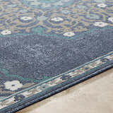 Close-up of the Penland Area Rug showing a navy, teal, taupe, and white floral pattern and machine woven texture. Texture