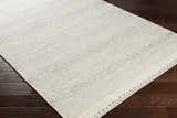 Close-up of the flat woven texture of the Penticton Cream Wool Rug on dark wood flooring. Corner