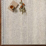 Close-up of the Penticton Cream Flat Woven Wool Rug showing its texture, beige tones, and gray border on a wood floor. Styleshot
