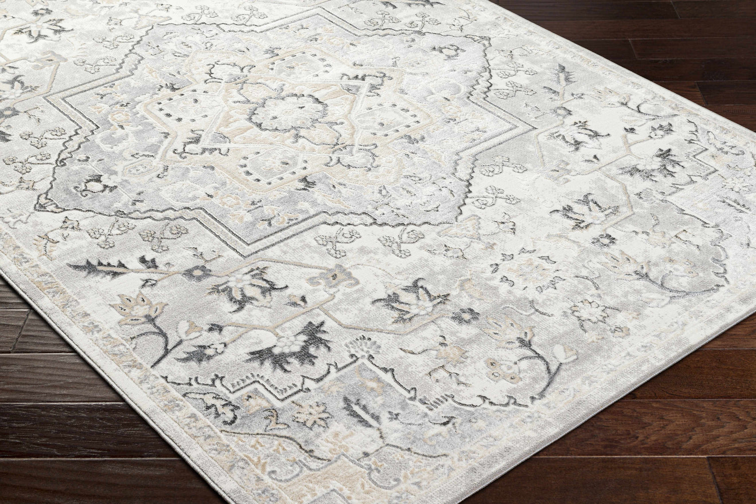 Close-up of the Phyre Area Rug in light gray, showcasing its traditional floral and geometric pattern on dark wood floors. Corner