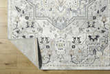 Close-up of the Phyre Area Rug showcasing its light gray, traditional floral pattern and soft texture on a wood floor. Fold