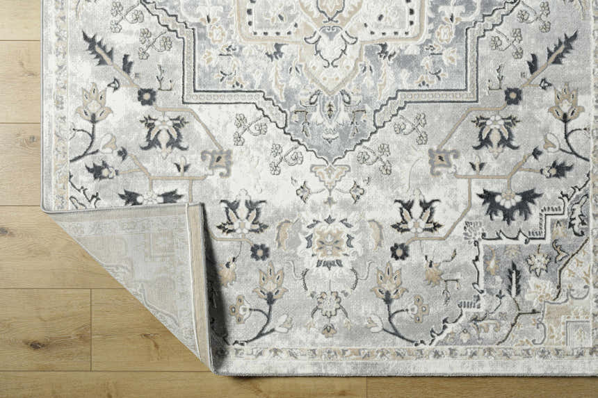 Close-up of the Phyre Area Rug showcasing its light gray, traditional floral pattern and soft texture on a wood floor. Fold