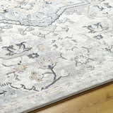 Close-up of Phyre Area Rug. Light gray farmhouse style rug with a traditional floral pattern and soft texture. Texture