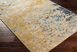 Close-up of the Pias Area Rug showing its beige, gray, and blue contemporary pattern and hand-knotted texture on dark wood floor. Corner