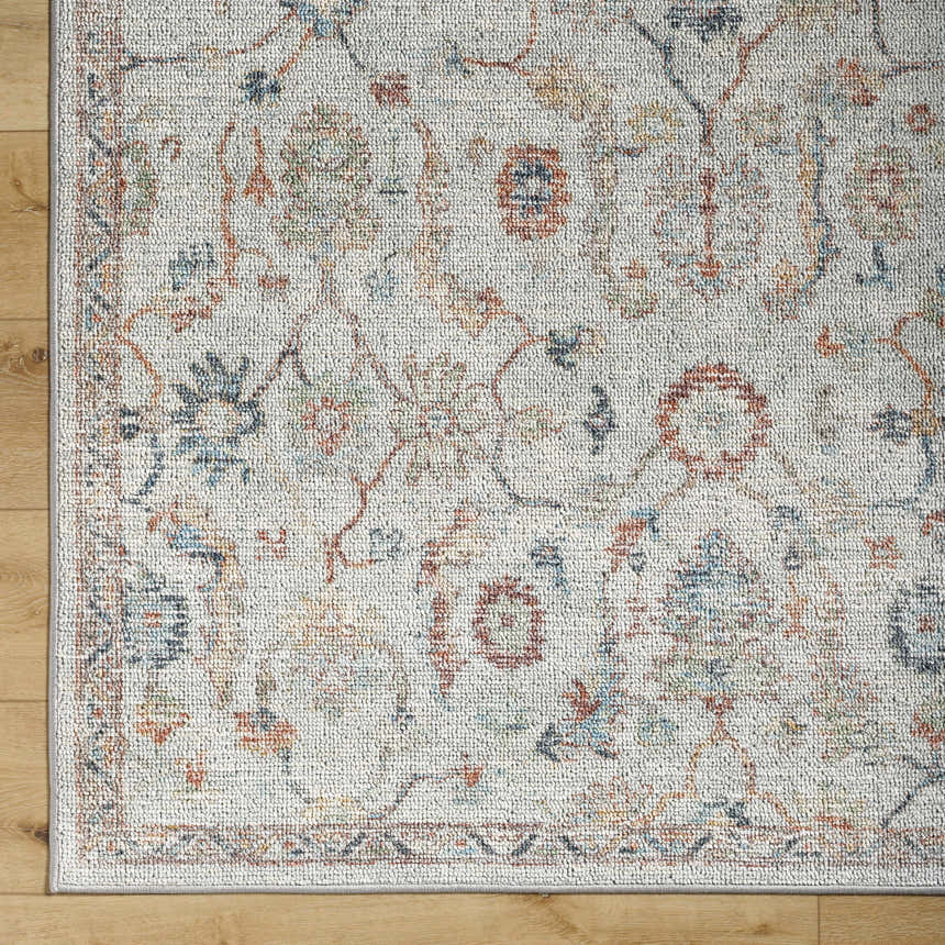 Close-up of Piera Washable Area Rug. Ash, light gray, silver tones, traditional floral pattern, machine woven texture. Corner