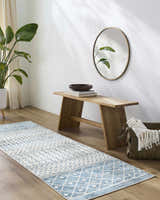 Entryway with Pinamopoan Washable Area Rug in blue and beige, wood bench, round mirror, and green plant. Roomscene-Runner