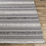 Close-up of the Planada Washable Area Rug. Black and cream cotton rug with a geometric, bohemian-inspired pattern. Front