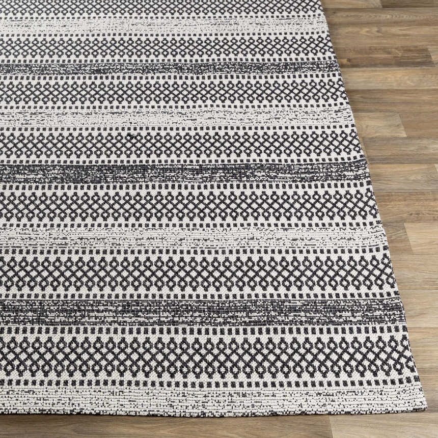 Close-up of the Planada Washable Area Rug. Black and cream cotton rug with a geometric, bohemian-inspired pattern. Front
