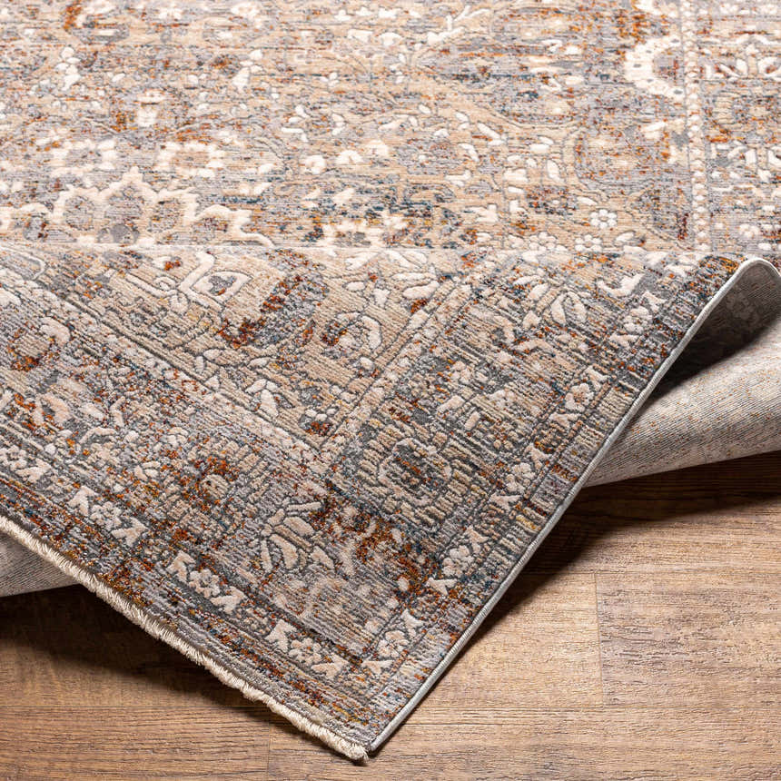 Close up of the Pambujan Area Rug showing beige, blue, and burnt orange traditional floral pattern and texture. Fold