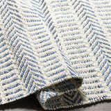 Close-up of the hand woven Pontian Area Rug. Beige jute rug with a contemporary blue and black chevron pattern. Fold