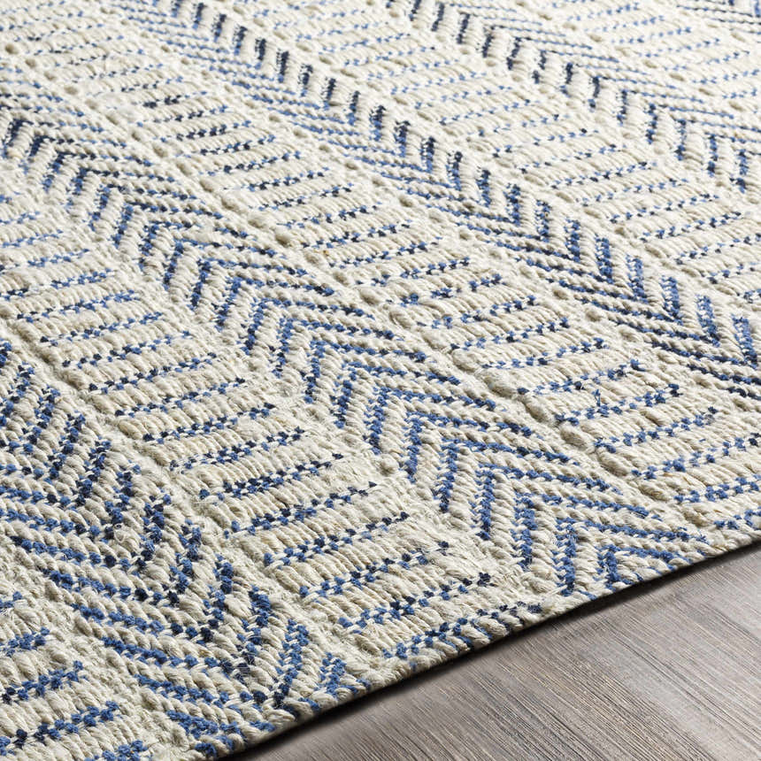 Close-up of the hand woven Pontian Area Rug. Beige jute rug with a blue herringbone pattern. Coastal farmhouse style. Texture