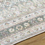 Close-up of the PNW Home Rainier Damask Green Washable Rug. Traditional floral pattern in green, red, and cream. Texture