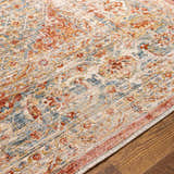 Close-up of the Polomolok Luxe Performance Rug. Traditional oriental design in cream, brick red, burnt orange, and denim blue. Texture