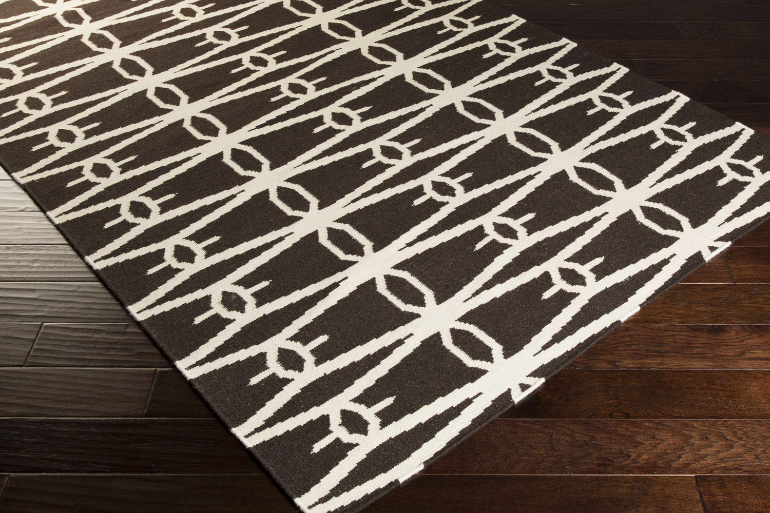 Close-up of the Potsdam Area Rug, a hand-woven wool rug with a dark brown and peach geometric design. Corner