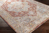 Close-up of the Powassan Area Rug showing its brick red, charcoal, and light beige traditional pattern. Corner
