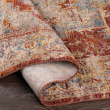Close-up of the Powassan Area Rug showing its brick red, teal, and beige traditional pattern and soft texture. Fold