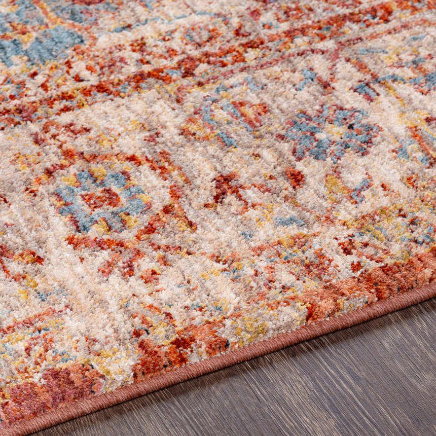 Close-up of the Powassan Area Rug showing its brick red, teal, and beige traditional pattern and soft texture. Texture