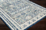 Close-up of the Purdys Area Rug featuring a Bohemian-style pattern in aqua, charcoal, and cream on a dark wood floor. Corner