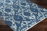 Close-up of the Premier Area Rug Clearance, a hand-woven cotton rug with a blue floral pattern on dark wood flooring. Corner