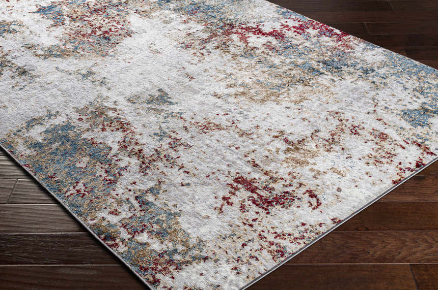 Close-up of the Prinza Area Carpet: a contemporary rug in dark gray, gray, and nutmeg with a distressed abstract pattern. Corner