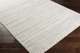 Close-up of the Parmelia Area Rug showing its off-white base and charcoal geometric pattern on dark wood floors. Corner