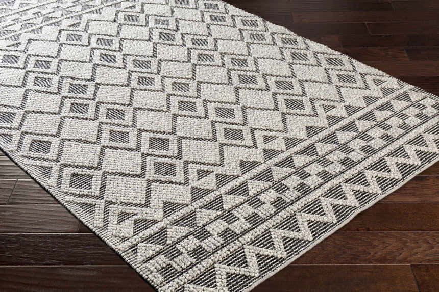 Close-up of the hand woven Post Area Rug. Bohemian style runner rug with a geometric design in ivory and black. Corner