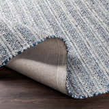 Close-up of the hand-loomed Potterspury Area Rug, showing blue, cream, and gray wool blend texture and backing. Fold