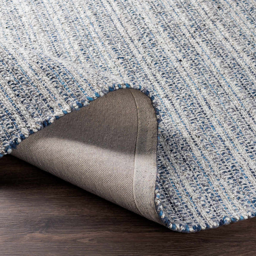 Close-up of the hand-loomed Potterspury Area Rug, showing blue, cream, and gray wool blend texture and backing. Fold