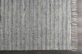 Close up of the hand-loomed Potterspury Area Rug. Blue and cream wool blend with a striped design and fringed edge. Corner