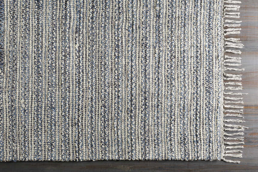 Close up of the hand-loomed Potterspury Area Rug. Blue and cream wool blend with a striped design and fringed edge. Corner