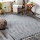Living room scene with a blue and cream Potterspury Area Rug, gray chair, and wooden accents. Contemporary style. Roomscene-Rectangle