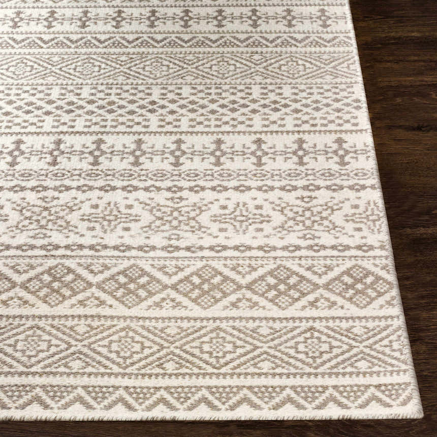 Close-up of the Pumwani Area Carpet. Cream wool rug with gray geometric, diamond, and tribal-inspired patterns. Front