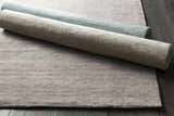 Close-up of the textured Barree Area Carpet, a white hand-loomed viscose rug, rolled and ready for a bathroom, kitchen, or mudroom. Styleshot