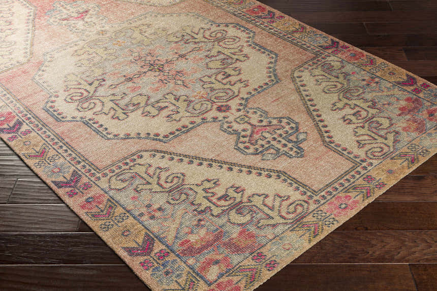 Close-up of the Queenscliff Rug featuring a traditional Persian design with beige, pink, and blue hues on a dark wood floor. Corner