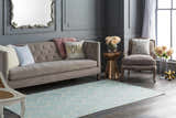 Living room scene with a Ragan Ice Blue Trellis Cotton Rug, gray walls, and a tufted sofa with decorative pillows. Roomscene-Rectangle