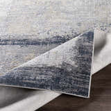 Close-up of the Rainworth Modern Slate Luxe Rug showing charcoal, beige, and gray tones and machine-woven texture. Fold