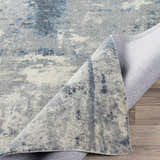 Close-up of the Ramsbottom Area Rug, showcasing its blue, charcoal, and cream contemporary pattern and woven texture. Fold