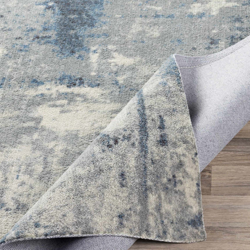 Close-up of the Ramsbottom Area Rug, showcasing its blue, charcoal, and cream contemporary pattern and woven texture. Fold