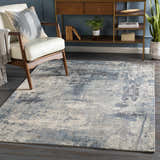Living room scene with a Ramsbottom Area Rug in blue, cream, and charcoal, styled with a modern chair and wood console table. Roomscene-Rectangle