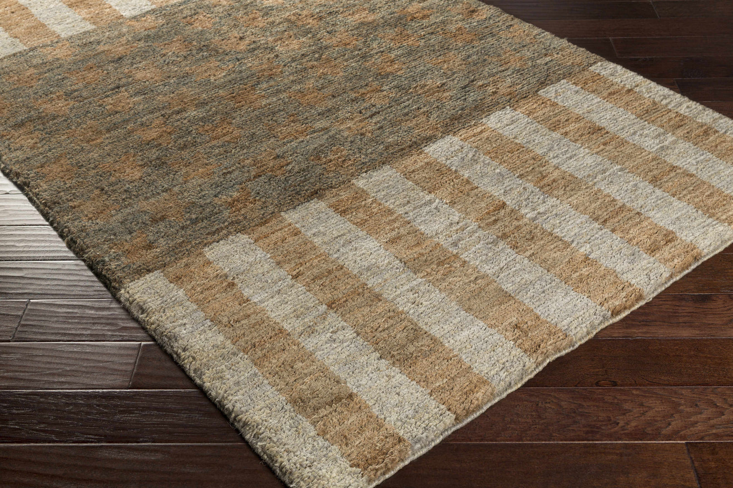Close-up of the Randleman Jute Rug showing its brown, dark green, and gray tones with a striped and block pattern. Corner