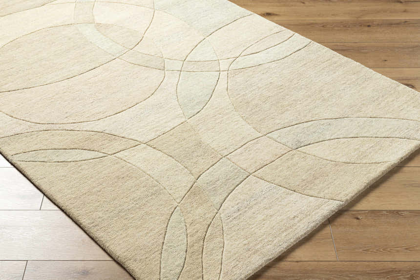 Close-up of the Rollo Area Rug. Ash, pearl, and tan wool rug with a contemporary geometric circle pattern. Corner