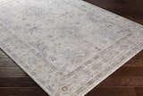 Close-up of Rochedale Area Rug. Cream rug with traditional lavender and olive floral pattern on dark wood floor. Corner